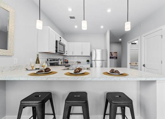 A kitchen with white cabinets and a marble countertop.