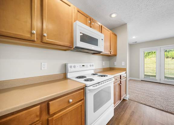 A kitchen with wooden cabinets and a white stove top oven.