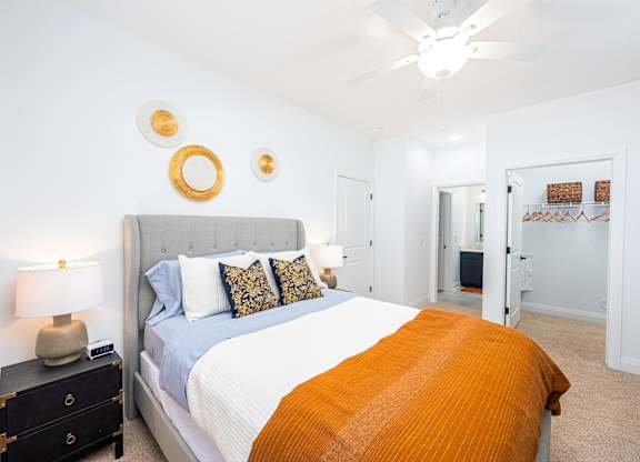 A bedroom with a bed, nightstand, and a ceiling fan.