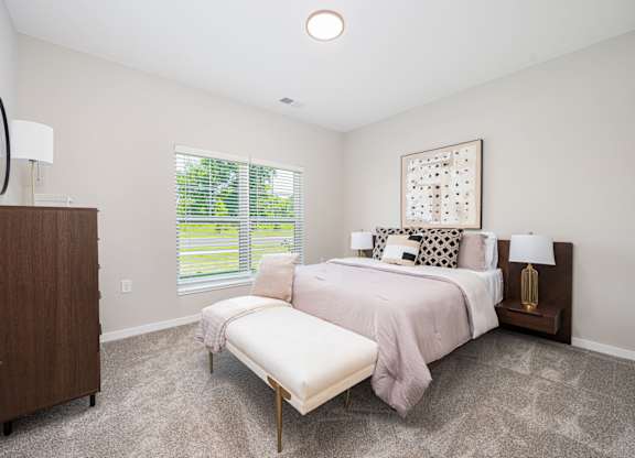 A bedroom with a large bed and a window with blinds.