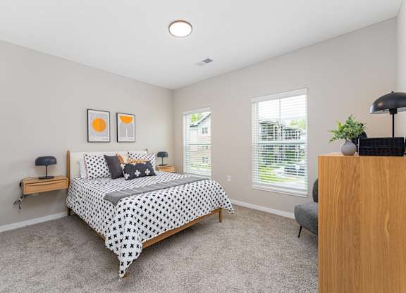 A bedroom with a bed, nightstand, and a window.