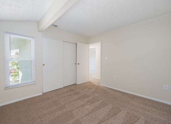 a spacious living room with carpet and a door to a bedroom