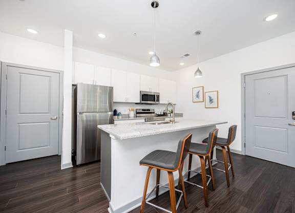 A kitchen with a white island and wooden chairs.