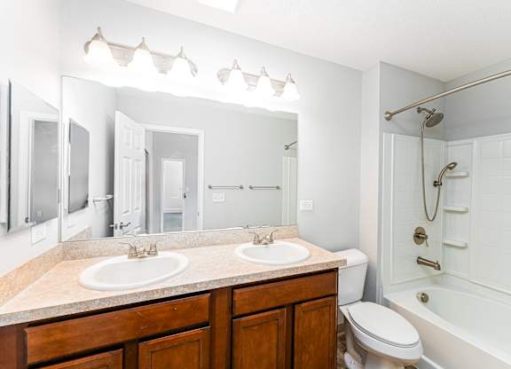 A white bathroom with a double sink and a toilet.