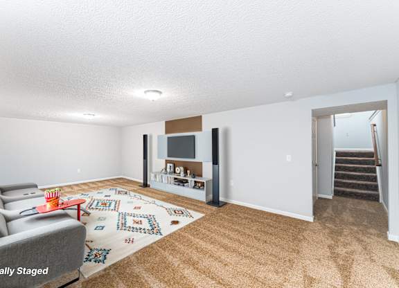 A living room with a grey couch and a rug with a pattern on it.