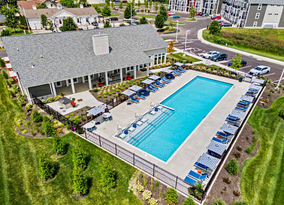 An aerial view of a pool surrounded by chairs and a building in the background.