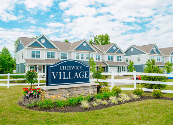 the village apartments sign in front of fence and building