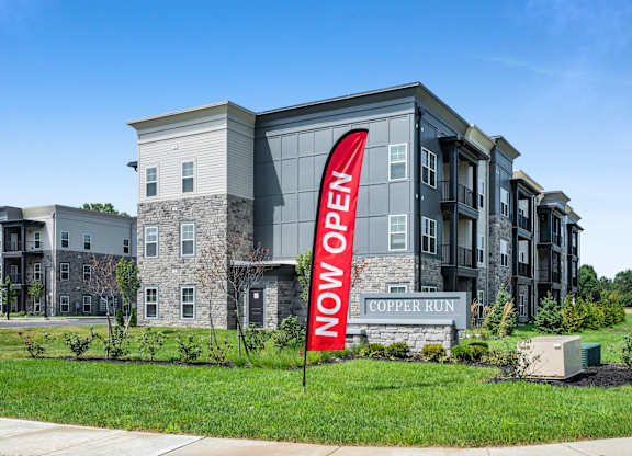 A sign in front of a building that says "Now Open".