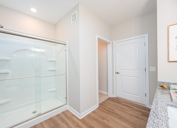 a bathroom with a glass shower and a door to a closet