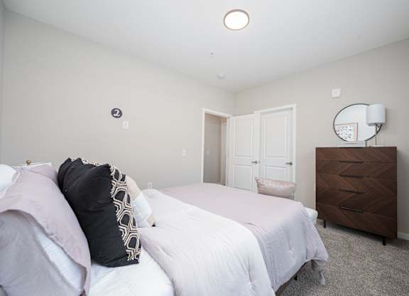 A bedroom with a bed, dresser, and mirror.