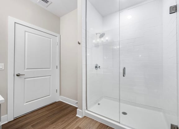 A white bathroom with a walk-in shower and a door.