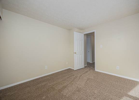 A room with a carpeted floor and a white door.