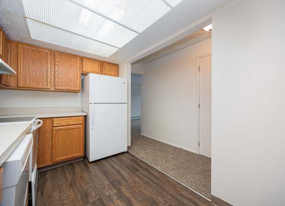 A kitchen with a white refrigerator and wooden cabinets.