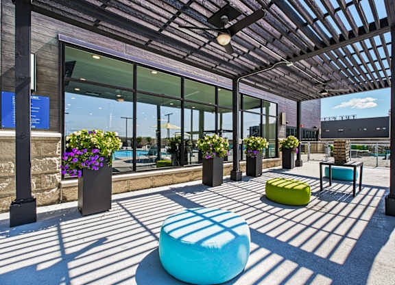 A sunny day at the outdoor seating area of a modern building with a blue bench and a yellow ottoman.