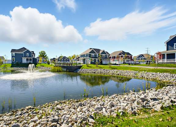 A pond with a fountain in the middle of a residential area.