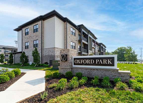 A sign that says Oxford Park in front of some buildings.