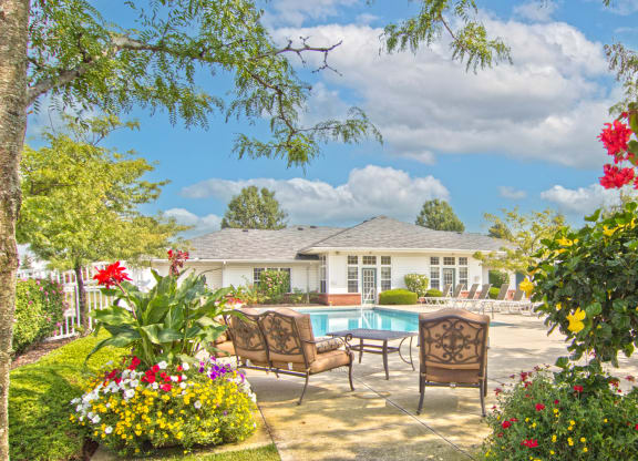 a backyard with a pool and chairs and flowers