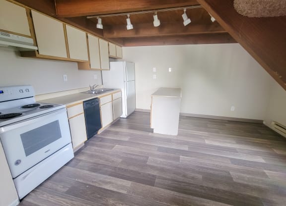 a kitchen with white appliances and a wooden floor