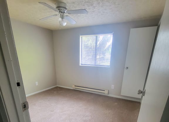 an empty room with a ceiling fan and a window