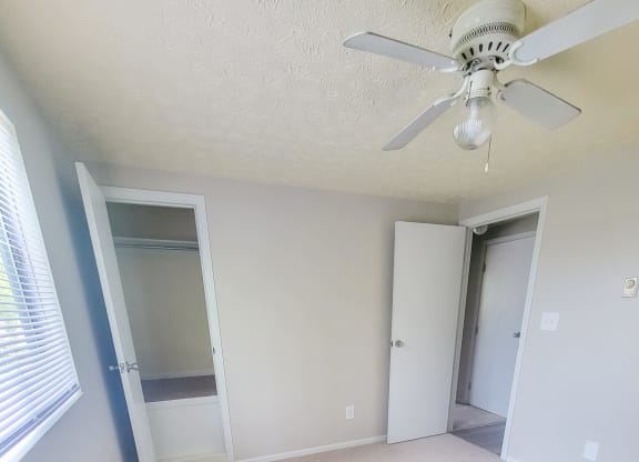 an empty bedroom with a ceiling fan