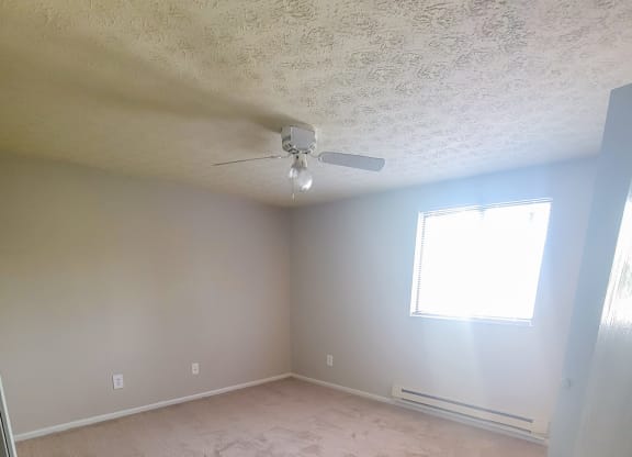an empty room with a ceiling fan and a window
