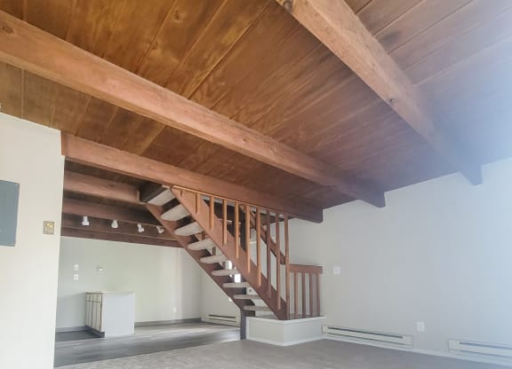 a large room with a wooden ceiling and stairs to the second floor