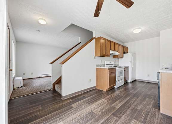 A kitchen with wooden floors and a staircase.