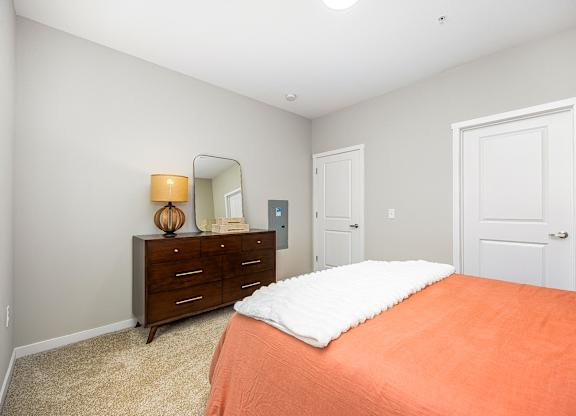 A bedroom with a bed, dresser, and mirror.