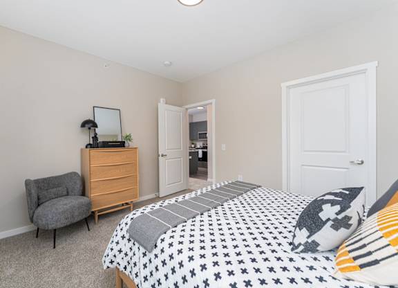 A bedroom with a bed, chair, and dresser.
