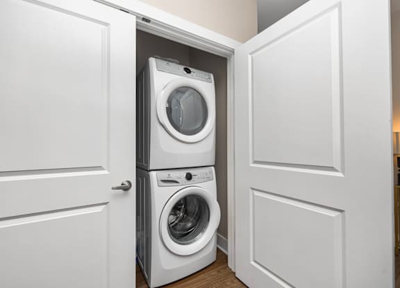 A white washing machine is in a white cabinet.