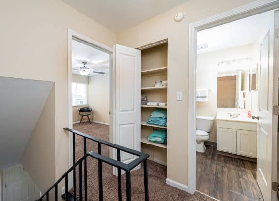 a stairway leading to a bathroom and a hallway with a closet