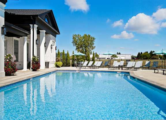 A swimming pool in front of a house with white columns.