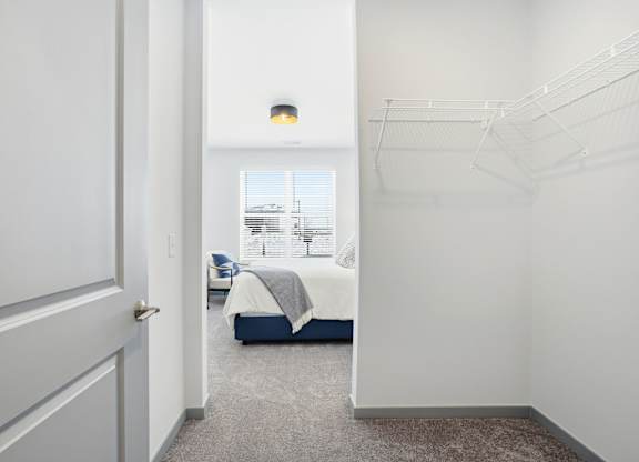 A bedroom with a bed, a chair, and a window.