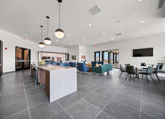 A modern kitchen with a large island and a dining area with chairs.