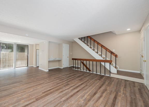 the living room and entryway of a house with a hard wood floor and stairs