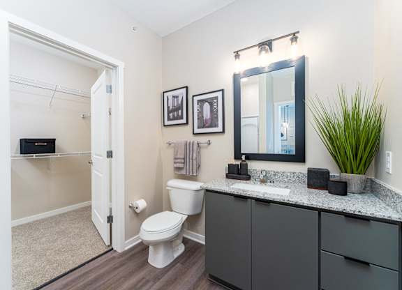 A bathroom with a toilet, sink, and mirror.