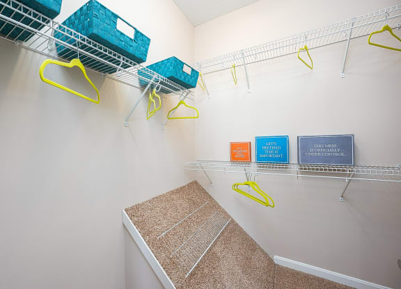 an empty closet with baskets and hooks on the wall