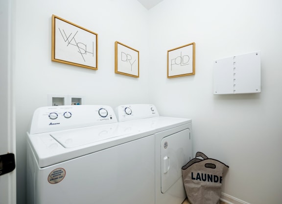 a washer and dryer in a laundry room with three pictures on the wall