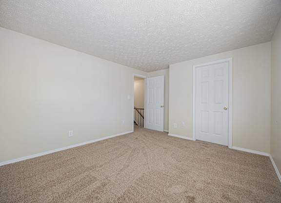 A room with carpeted floor and two doors.