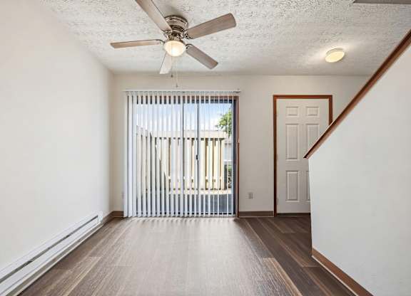 A room with a ceiling fan and a sliding glass door.