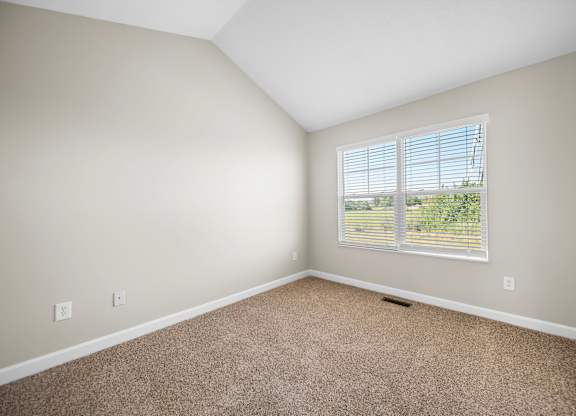 A room with a window and carpeted floor.