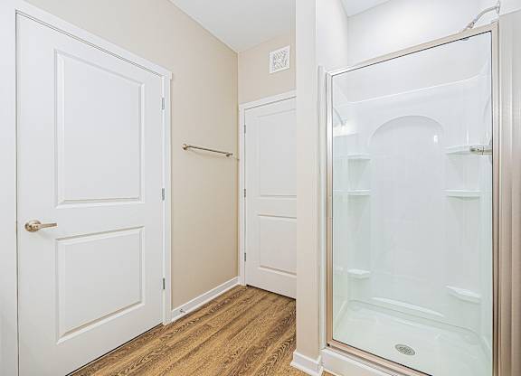 A white door is on the left and a glass shower door is on the right.