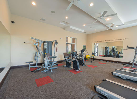 a gym with cardio equipment and weights in a building with white walls