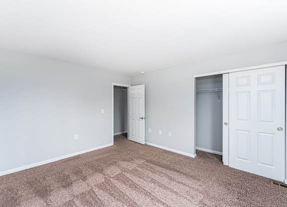 A room with a carpeted floor and two white doors.