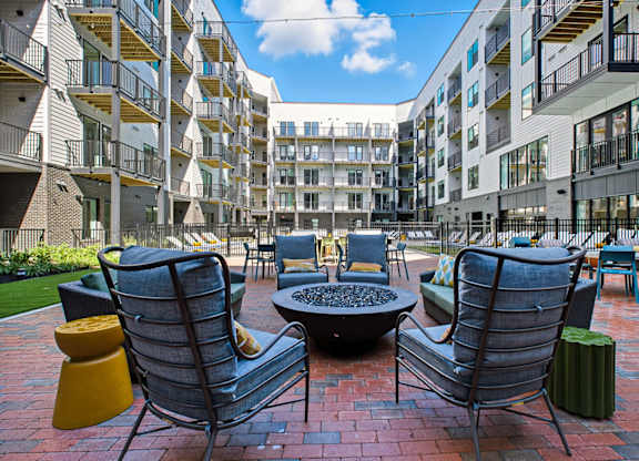 A patio with chairs and a table in front of apartment buildings.