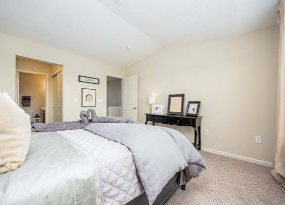 A bedroom with a large bed and a nightstand with a lamp.