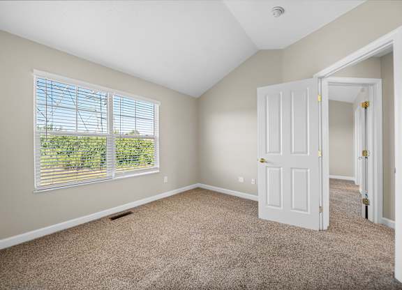 A room with a carpeted floor and a window with blinds.