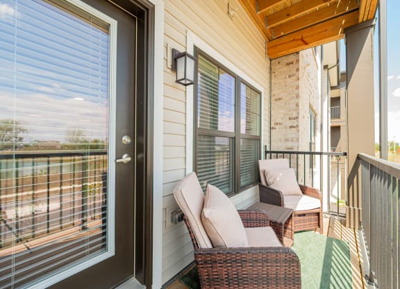 a porch with two wicker chairs and a glass door