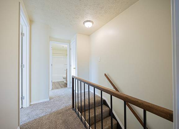A hallway with a staircase and a light on the ceiling.