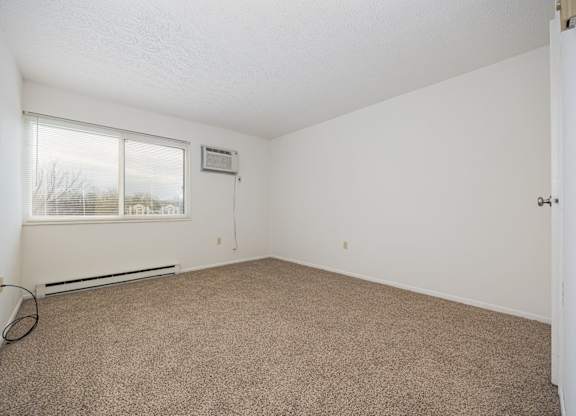A room with a carpeted floor and a window.